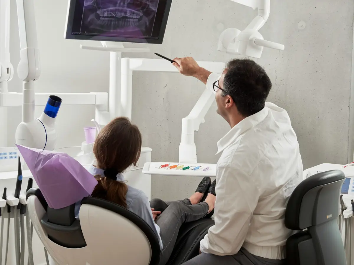 A dentist going over x-rays with a patient in the dental chair
